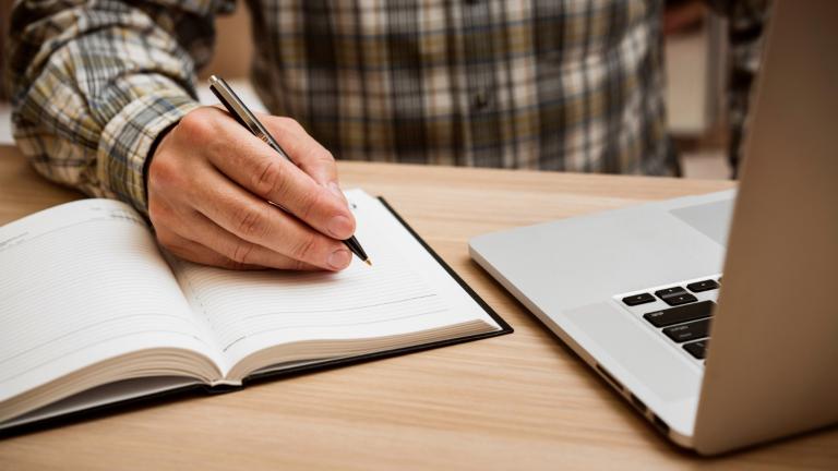 Persona escribiendo a mano y a computadora