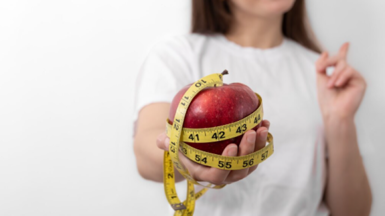 Mujer sosteniendo manzana con cinta de medir